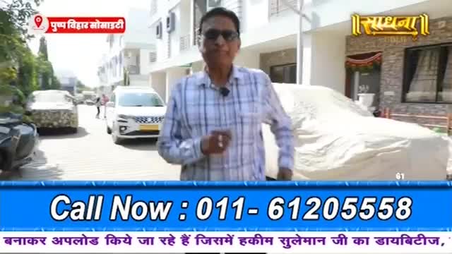 A man in a checkered shirt walks towards the camera on a street in India, with cars parked on either side. A white car is covered with a sheet in the foreground, and a Sadhna logo is visible on a building. A man in a checkered shirt walks towards the camera on a street in India, with cars parked on either side. A white car is covered with a sheet in the foreground, and a Sadhna logo is visible on a building.