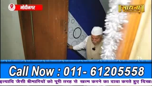 A man in a white cap and vest steps through a doorway. The "Sadhna" logo appears above him.