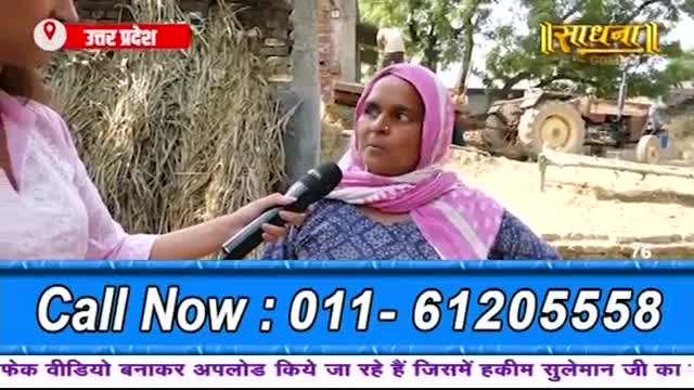 A woman in a pink headscarf speaks into a microphone held by a reporter. Behind them, a tractor sits idle in a dusty, rural Indian landscape.