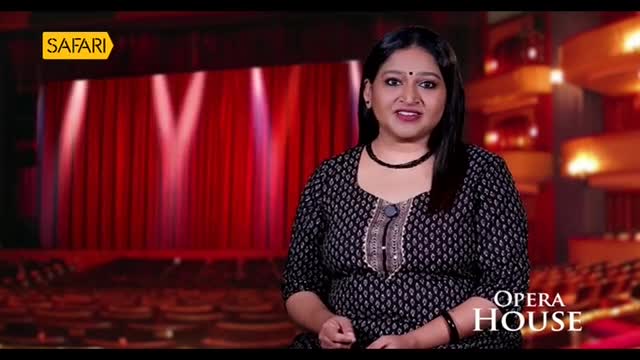 A woman in a patterned dress speaks directly to the camera, in front of a stage with red curtains and spotlights. The "Safari" logo is in the corner, and the words "Opera House" are displayed below.
