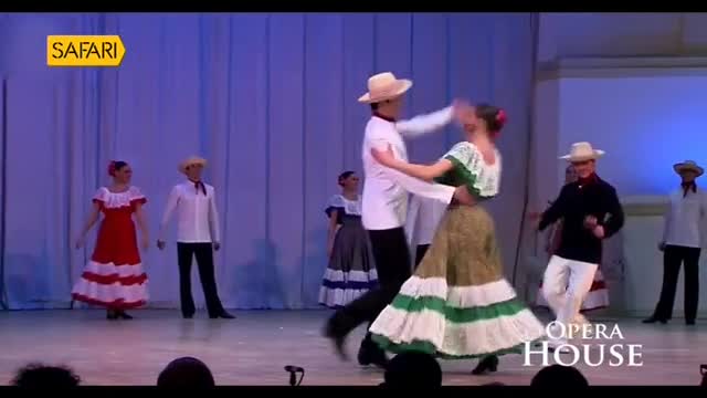A couple in straw hats and traditional dress twirls center stage, while other dancers stand ready. The Opera House performance, as seen on Safari TV, is underway.
