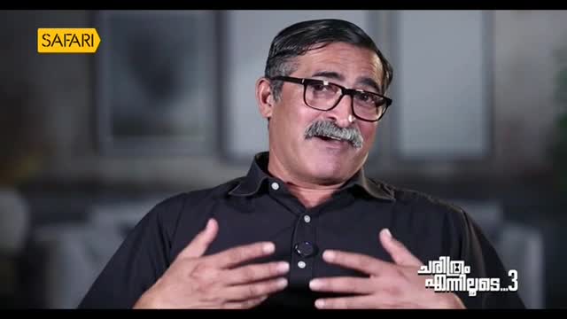 The man in the black shirt gestures with both hands, his face animated. A Safari TV logo appears in the top left corner.

