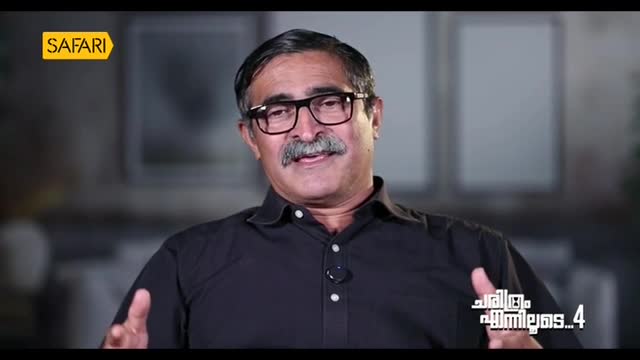 A man with a mustache and glasses gestures with his hands, speaking on Safari TV. The logo is visible in the upper left corner, and Malayalam text appears on the right.
