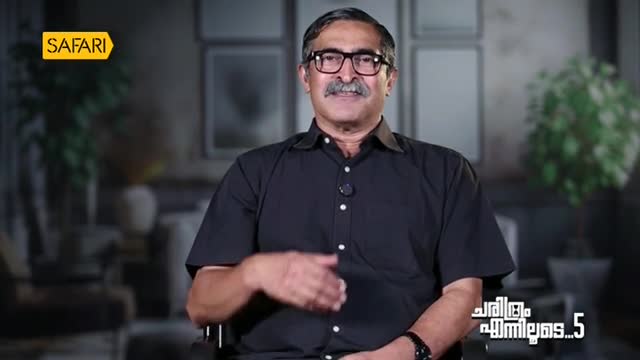 The man in the black shirt is gesturing with his right hand, smiling at the camera.  A "Safari" logo is in the top left corner, and the show's title is visible on the right.
