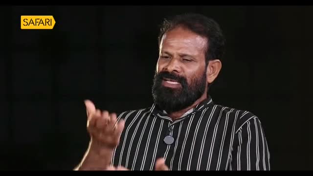 A man with a full beard and a striped shirt gestures with his hands as he speaks. The Safari TV logo is visible in the upper left corner.
A man with a full beard and a striped shirt gestures with his hands as he speaks. The Safari TV logo is visible in the upper left corner.