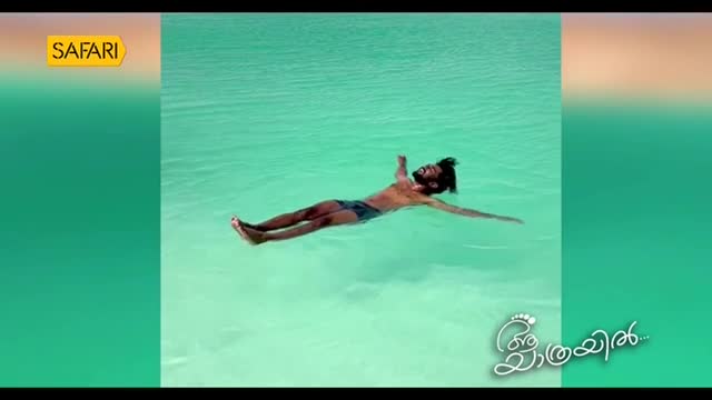 A man floats effortlessly on his back in the turquoise water. The Safari TV logo sits in the corner as the man drifts in the sun.
