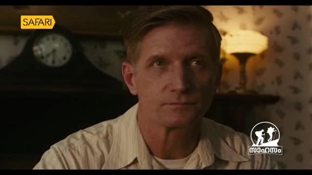 A man with short, light brown hair looks intently forward. The Safari TV logo is visible in the upper left corner, and a circular logo with figures and text in Malayalam appears in the lower right. A man with short, light brown hair looks intently forward. The Safari TV logo is visible in the upper left corner, and a circular logo with figures and text in Malayalam appears in the lower right.