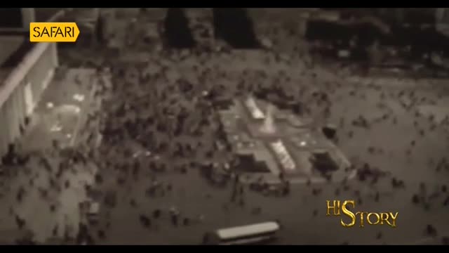 A vast crowd surges across the plaza, a river of people flowing around fountains and buildings. The scene, broadcast on Safari TV, captures a moment of intense movement in India. A vast crowd surges across the plaza, a river of people flowing around fountains and buildings. The scene, broadcast on Safari TV, captures a moment of intense movement in India.
