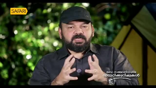 A man with a beard and a black cap gestures with his hands while speaking. The "Safari" logo appears in the upper left corner, and Malayalam text is visible on the right.