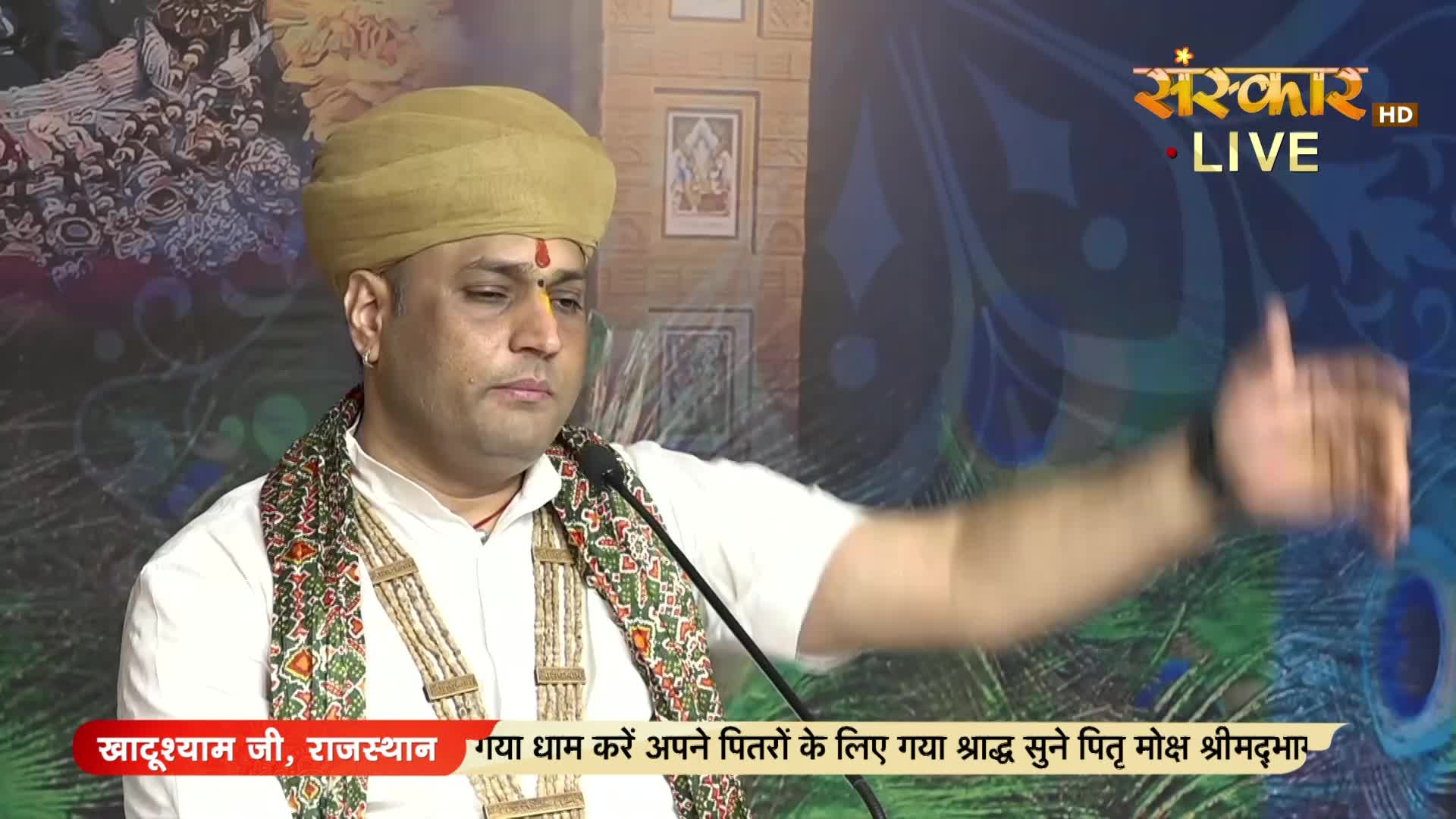 A man in a turban and traditional garb gestures with his right hand while speaking into a microphone. The Sanskar TV logo is visible in the top right corner, and a banner at the bottom identifies the speaker as being from Rajasthan.
