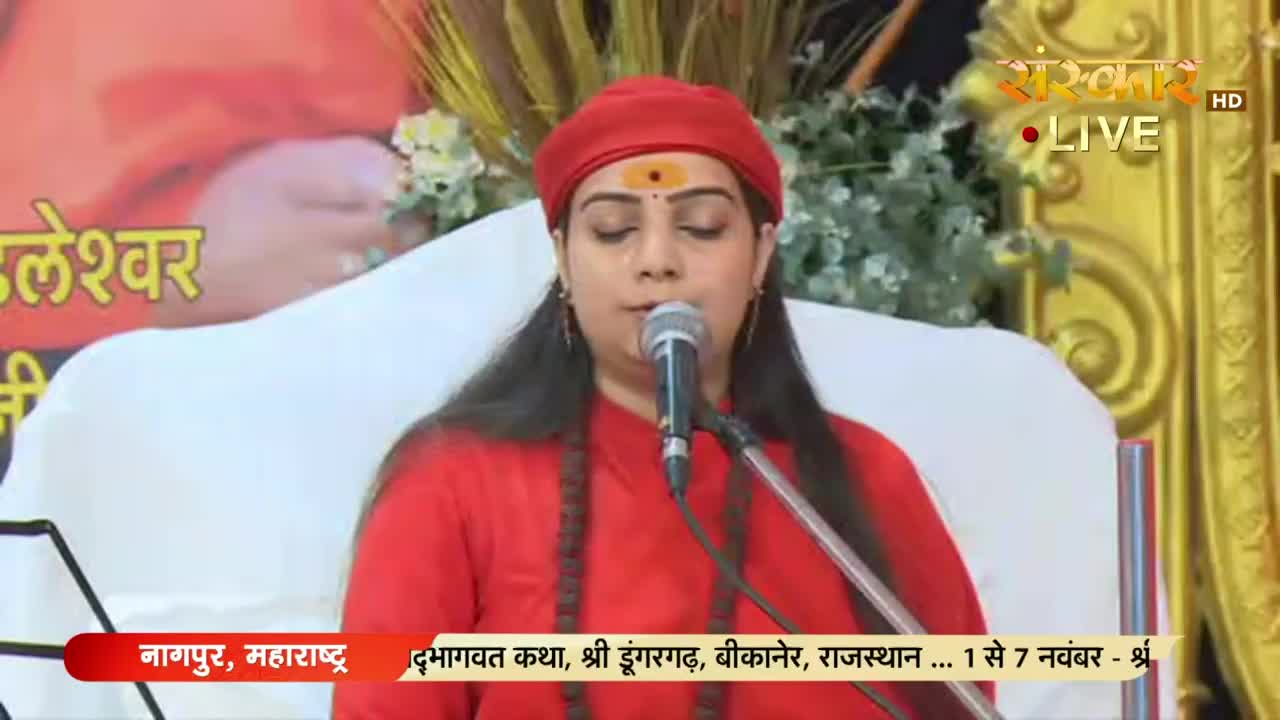 A woman in a red outfit and a matching cap speaks into a microphone, her face illuminated by studio lights. The Sanskar TV logo is visible in the corner, and a banner at the bottom indicates the event is in India.

