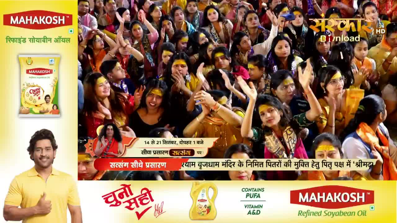 The crowd, many with yellow marks on their foreheads, raise their hands and look up, seemingly in prayer or celebration. A broadcast from Sanskar TV is underway, with a religious figure and advertisements for cooking oil visible in the frame.
