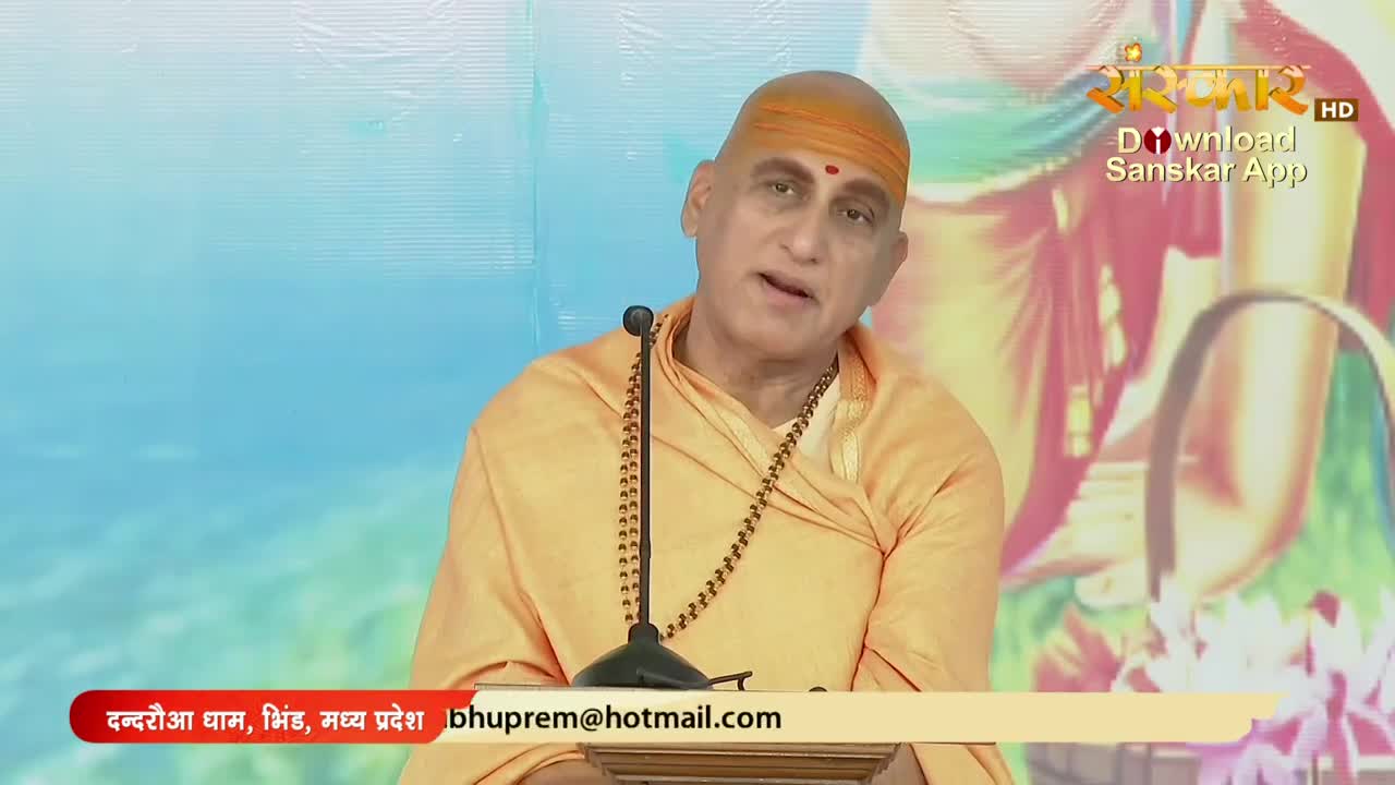 A man in saffron robes speaks into a microphone, his expression earnest. The Sanskar TV logo and a call to download the app are visible in the top right corner.
