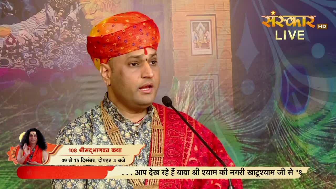 A man in a vibrant turban is speaking into a microphone, likely on Sanskar TV, with the words "108 Shrimad Bhagwat Katha" displayed on screen. Behind him, a backdrop of peacock feathers and a framed image create a colorful setting.
A man in a vibrant turban is speaking into a microphone, likely on Sanskar TV, with the words "108 Shrimad Bhagwat Katha" displayed on screen. Behind him, a backdrop of peacock feathers and a framed image create a colorful setting.