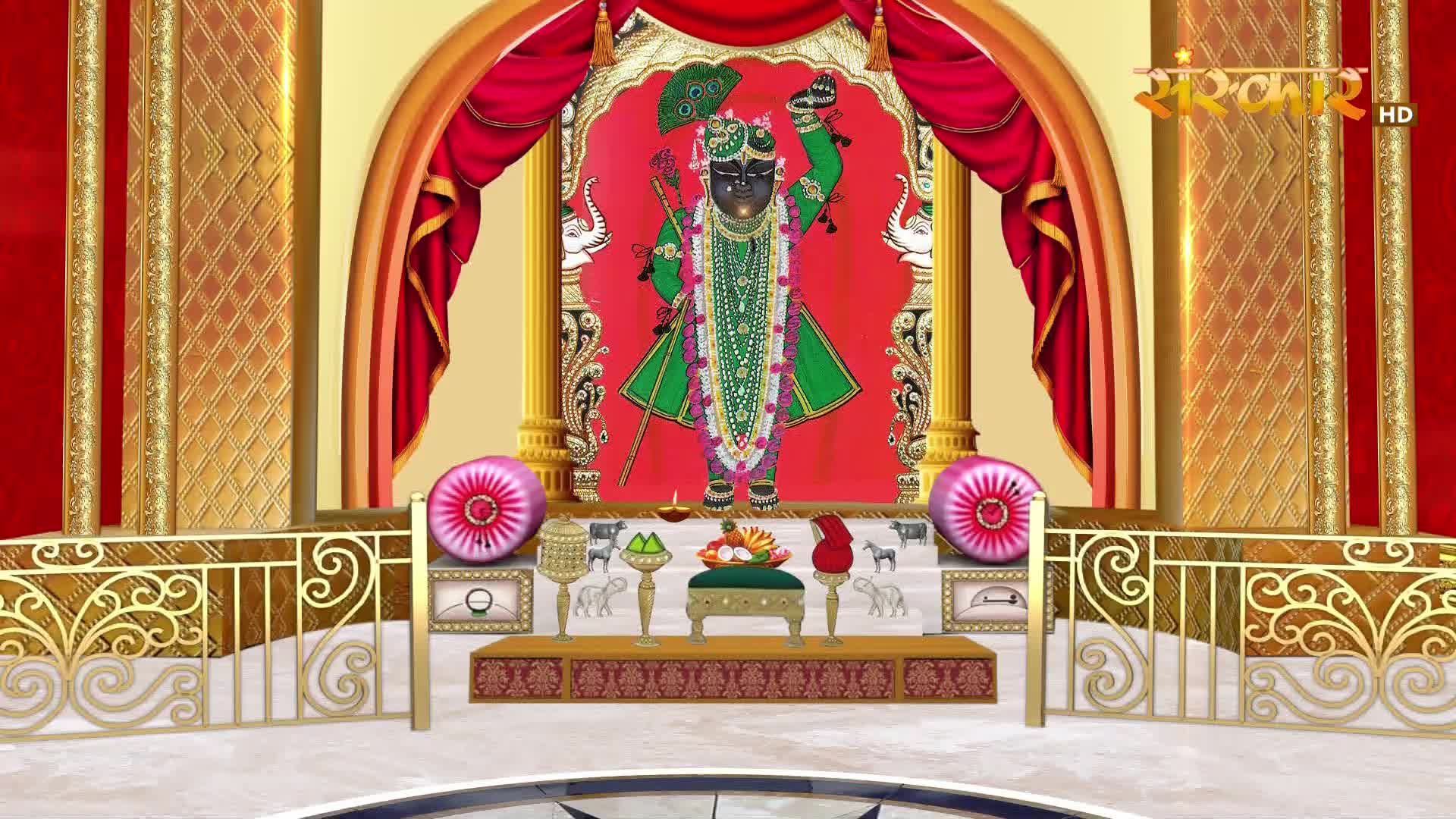 A dark-skinned deity stands adorned in green, a peacock feather in his crown. Red curtains frame the scene, and gold trim highlights the ornate stage.