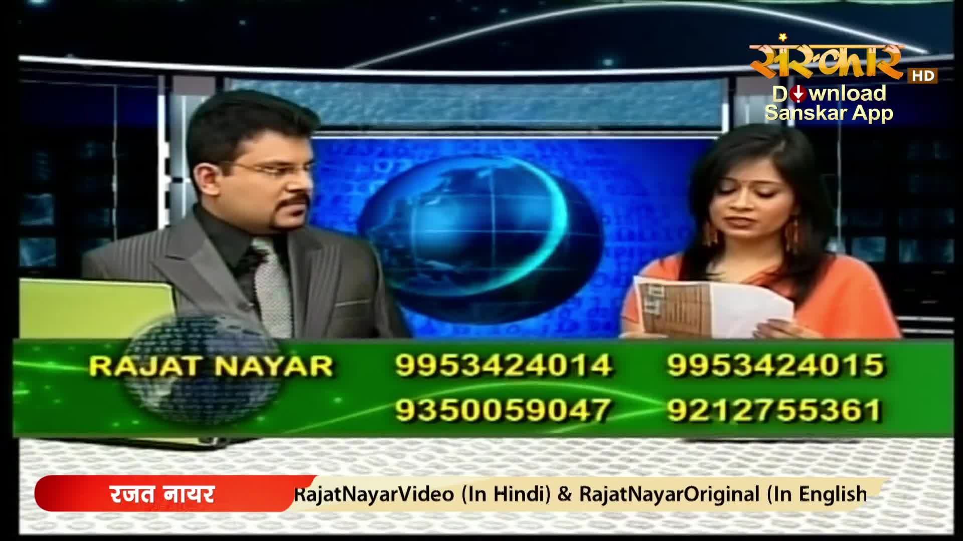 A man in a suit and glasses looks off-camera while a woman in an orange top reads from a paper. A graphic displays phone numbers and "Rajat Nayar" in English and Hindi.