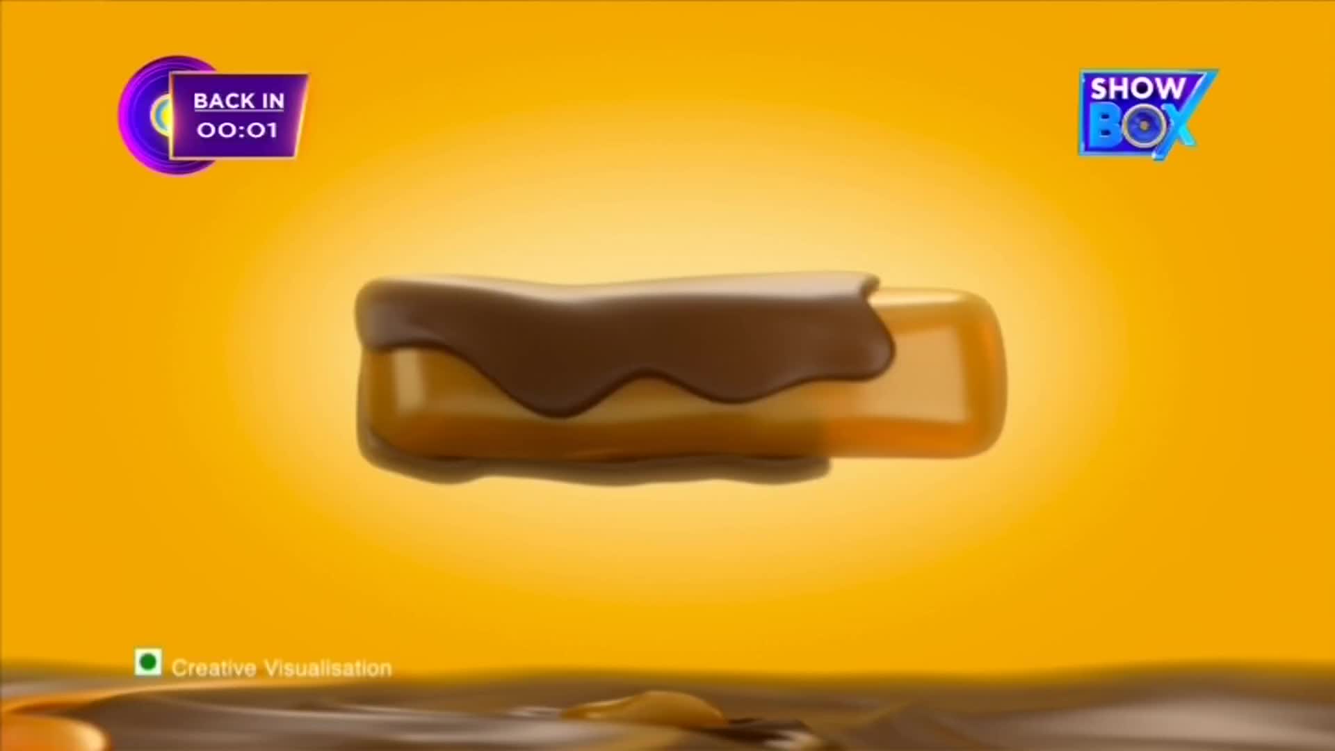 A candy bar, coated in dark chocolate, floats against a bright yellow background. The ShowBox logo and a countdown timer suggest this is an advertisement on Indian television.

