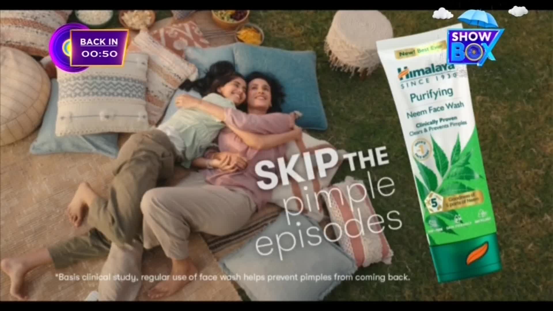 Two women are relaxing on a picnic blanket, embracing each other. A tube of Himalaya Neem Face Wash is displayed beside them, and a ShowBox logo appears in the corner.
