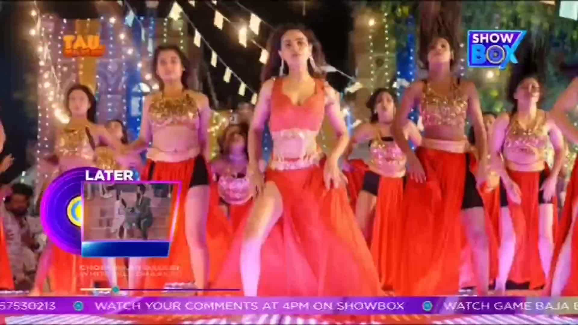 A group of women in red skirts and gold tops are dancing, their arms and heads moving in unison. The scene is from an Indian television show, with the ShowBox logo visible in the corner.

