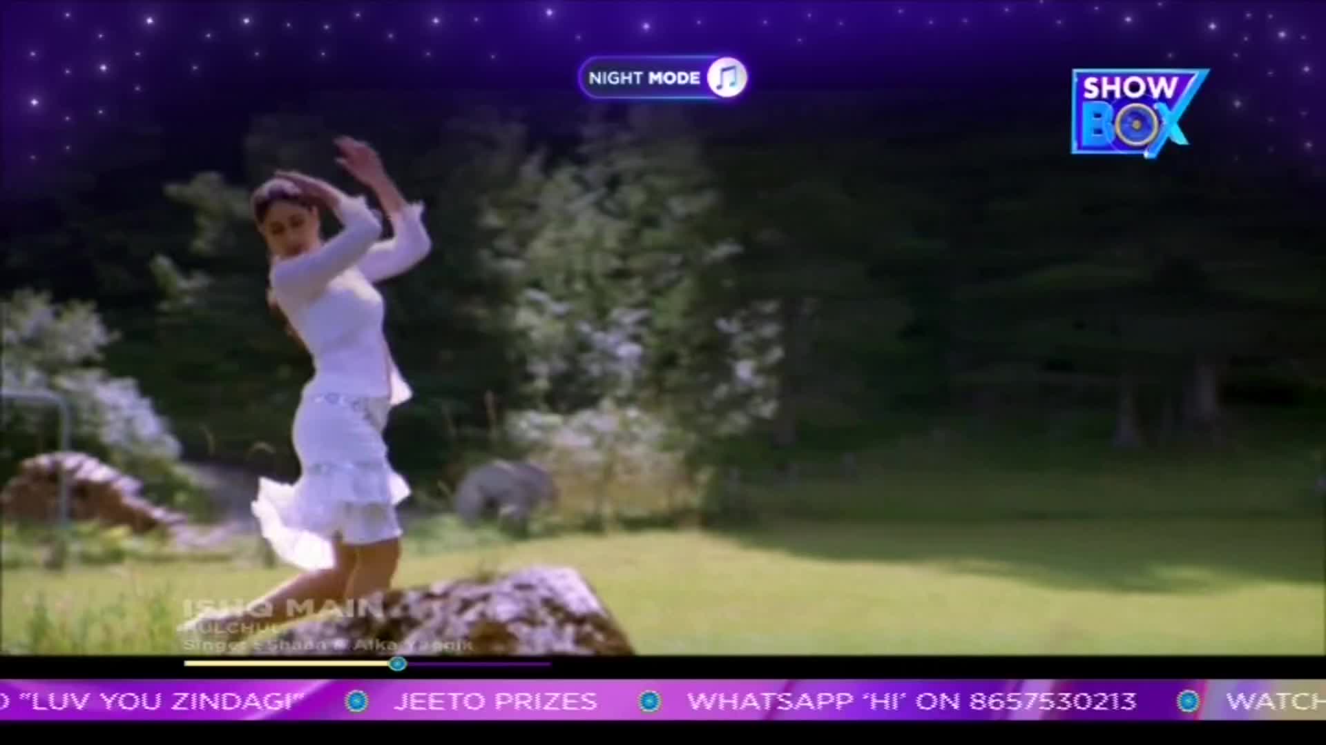 A woman in white dances on a rock, her arms raised in the air. The scene is playing on a ShowBox screen, with a purple night sky overlay.
