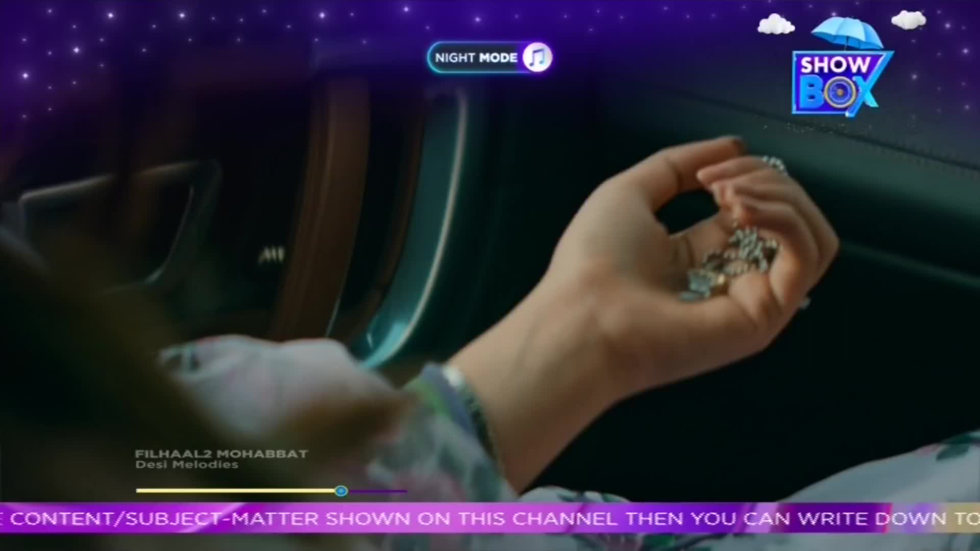 A hand, adorned with rings, holds a small, silver chain. The scene is dark, with a "Night Mode" indicator visible, and the ShowBox logo in the corner.
