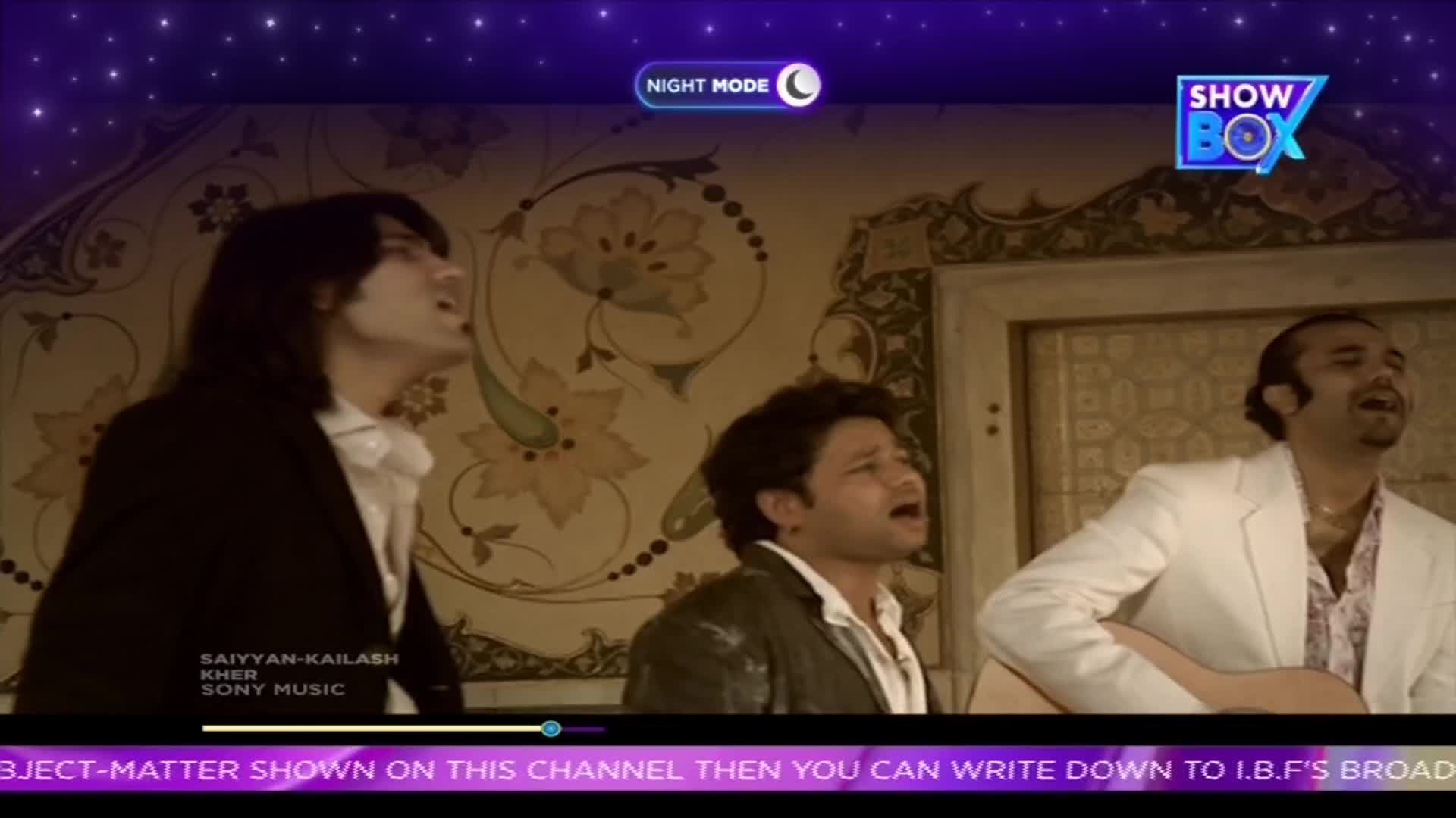 Three men are singing with passion, one playing a guitar, all with their eyes closed and mouths open. The scene is framed by a ShowBox logo and a starry night mode overlay.
