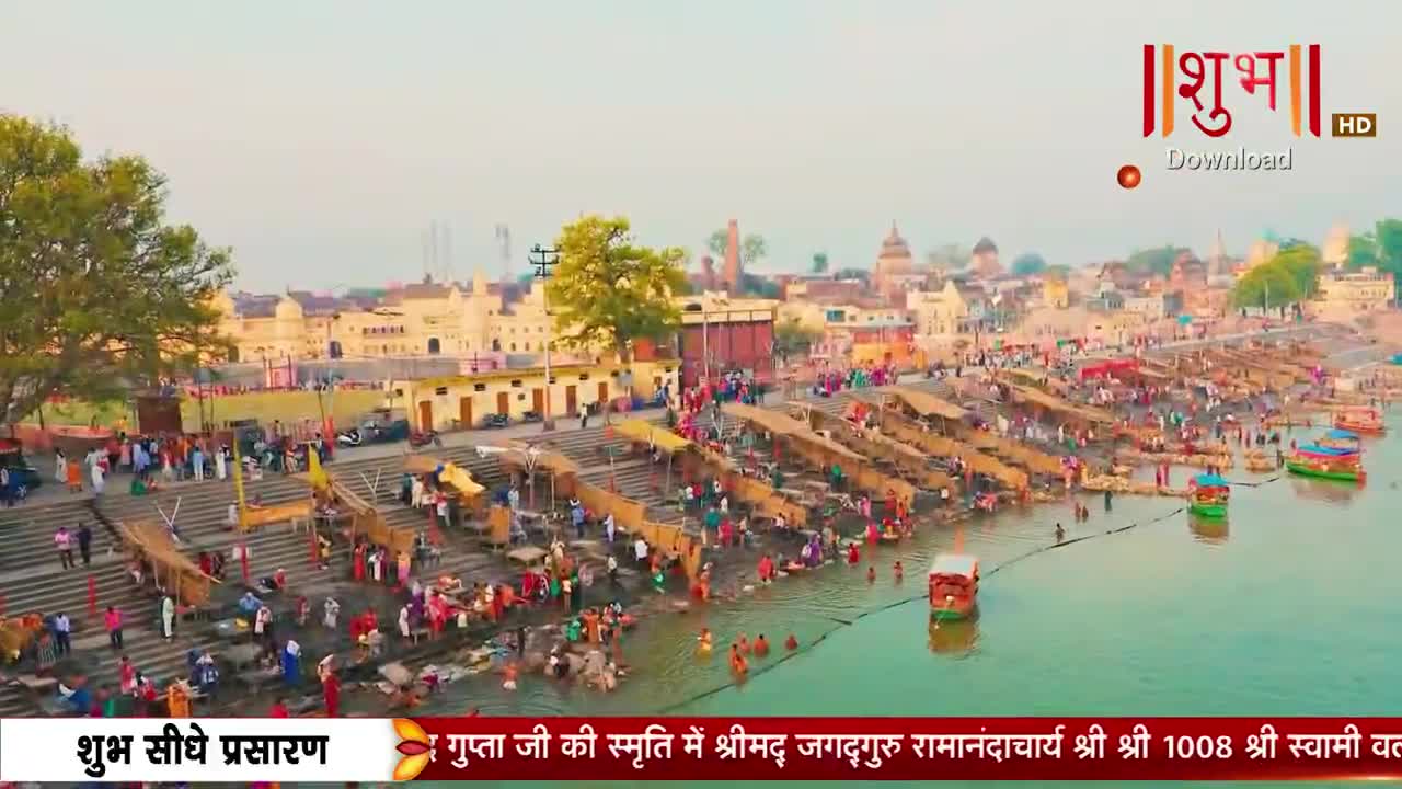 People are bathing in the river, while others stand on the steps and watch. The scene is being broadcast live on Shubh TV, with text at the bottom of the screen.
