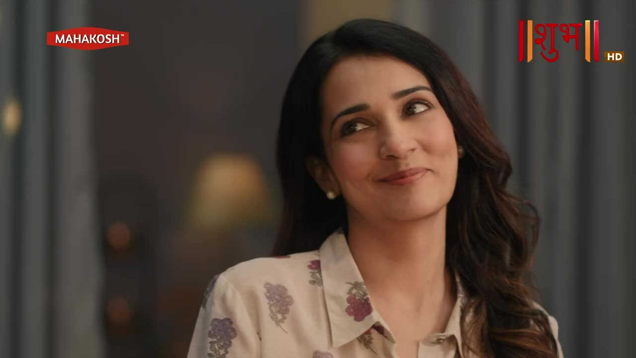 The woman in the floral shirt looks off to the side, a small smile playing on her lips. The Shubh TV logo is visible in the corner.
