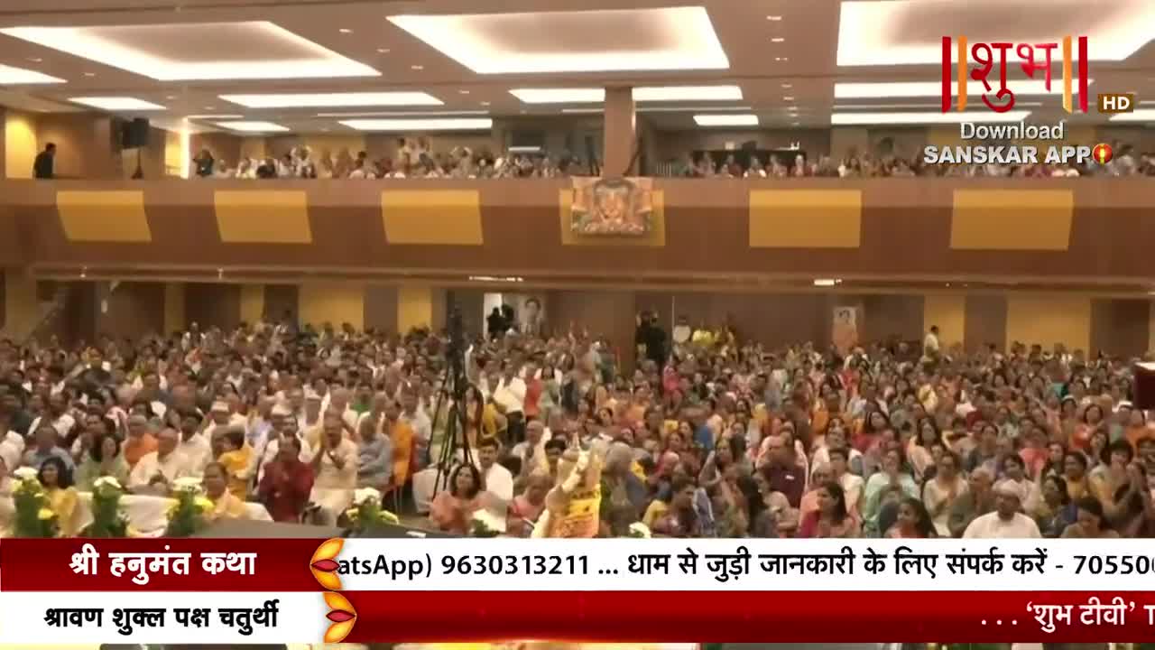 The crowd is packed tight, many with hands raised, as a speaker addresses them from the front. The event is being broadcast on Shubh TV, with details scrolling at the bottom of the screen.
