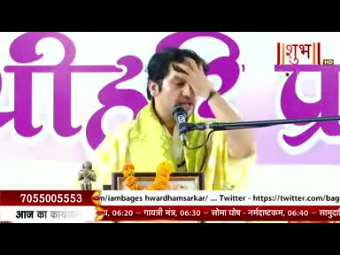 A man in a yellow shawl gestures with his hand, speaking into a microphone. The Shubh TV logo is visible, and the bottom banner lists the day's schedule in Hindi.
