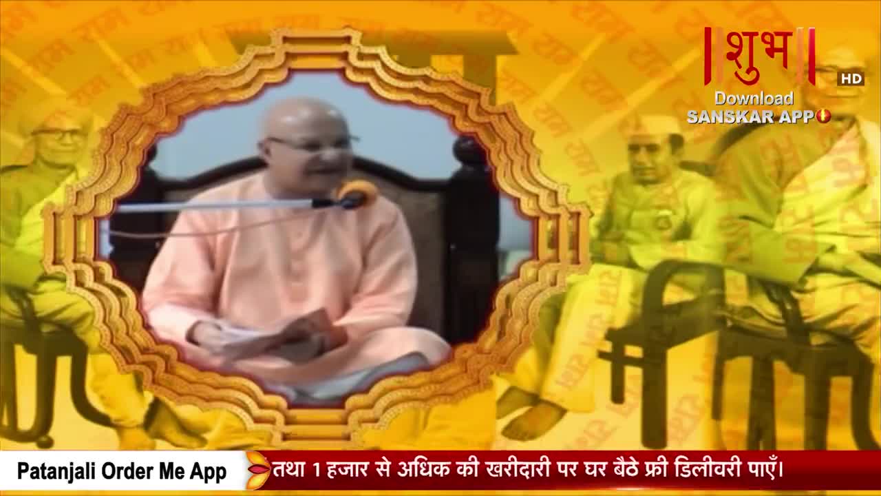 A man in a light orange robe speaks into a microphone, holding a paper in his hands. The Shubh TV logo and Hindi text overlay the scene, with faded images of other people in the background.
