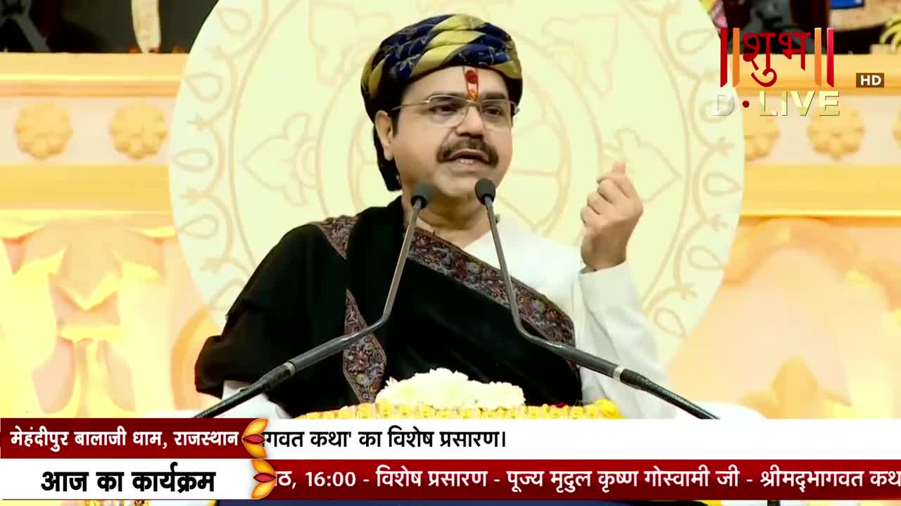 A man in a turban and glasses gestures with his right hand as he speaks into two microphones. The Shubh TV logo is visible in the top right corner, and text at the bottom indicates the broadcast is from India.
A man in a turban and glasses gestures with his right hand as he speaks into two microphones. The Shubh TV logo is visible in the top right corner, and text at the bottom indicates the broadcast is from India.