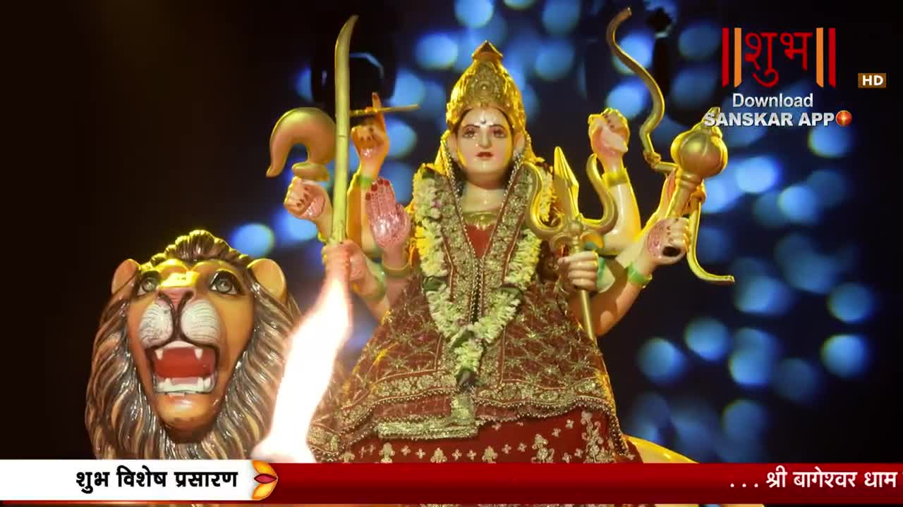 A vibrant idol of Goddess Durga, adorned in a red and gold sari, stands tall with multiple arms. Beside her, a fierce lion statue roars, its mouth agape as flames lick upwards.