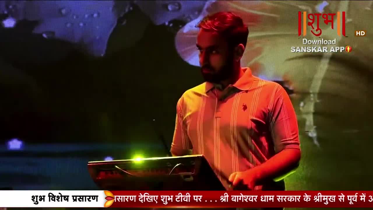A man in a striped polo shirt stands at a console, his hand resting on a keyboard. The Shubh TV logo glows in the background.