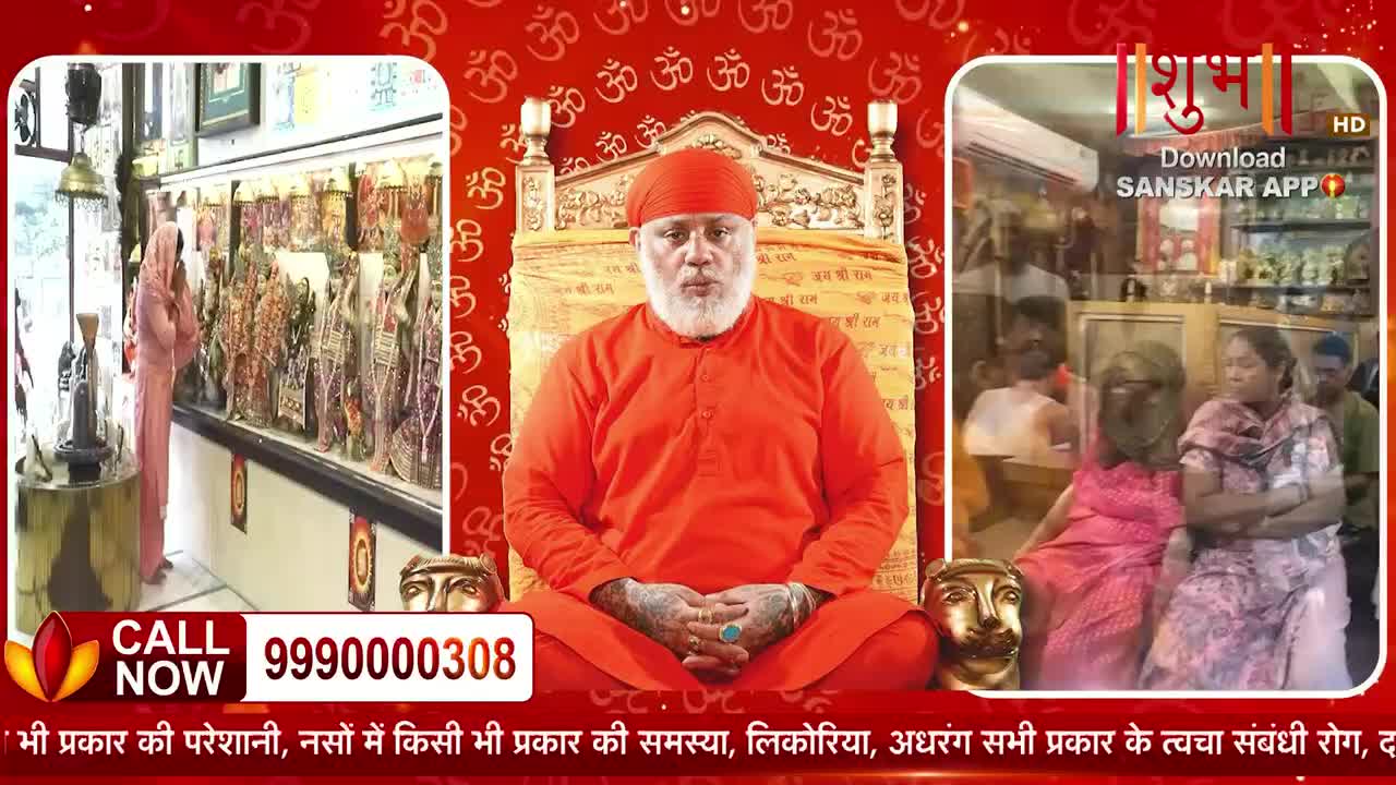 A man in an orange robe sits on a throne, his hands resting on his lap. To his left, a woman in a pink headscarf stands before a display of devotional items.