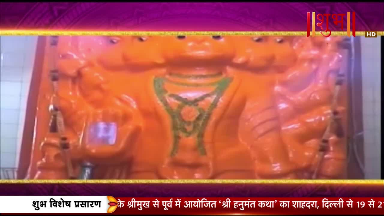 A large, bright orange statue of a multi-headed deity stands before me. A green garland drapes across its chest, and a Shubh HD logo is visible in the corner.