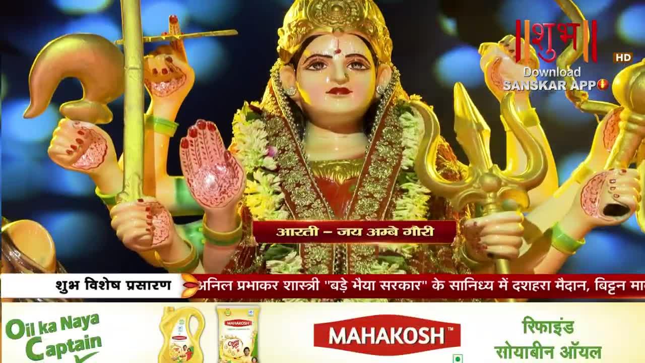 The goddess Durga, adorned with flowers, stands with multiple arms, one holding a trident. Below, the text "आरती - जय अम्बे गौरी" flashes, indicating a devotional song broadcast on Shubh TV.