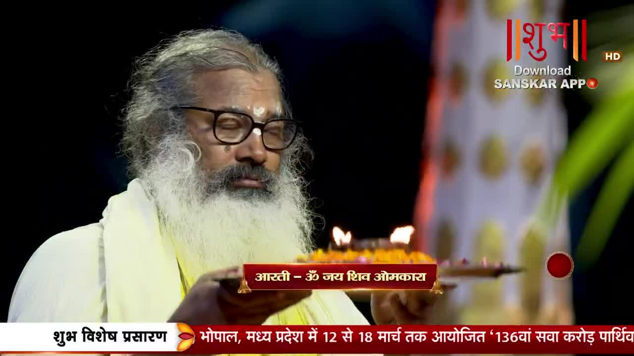 A man with a long white beard and glasses holds a tray with lit diyas. The Shubh TV logo appears in the upper right corner.