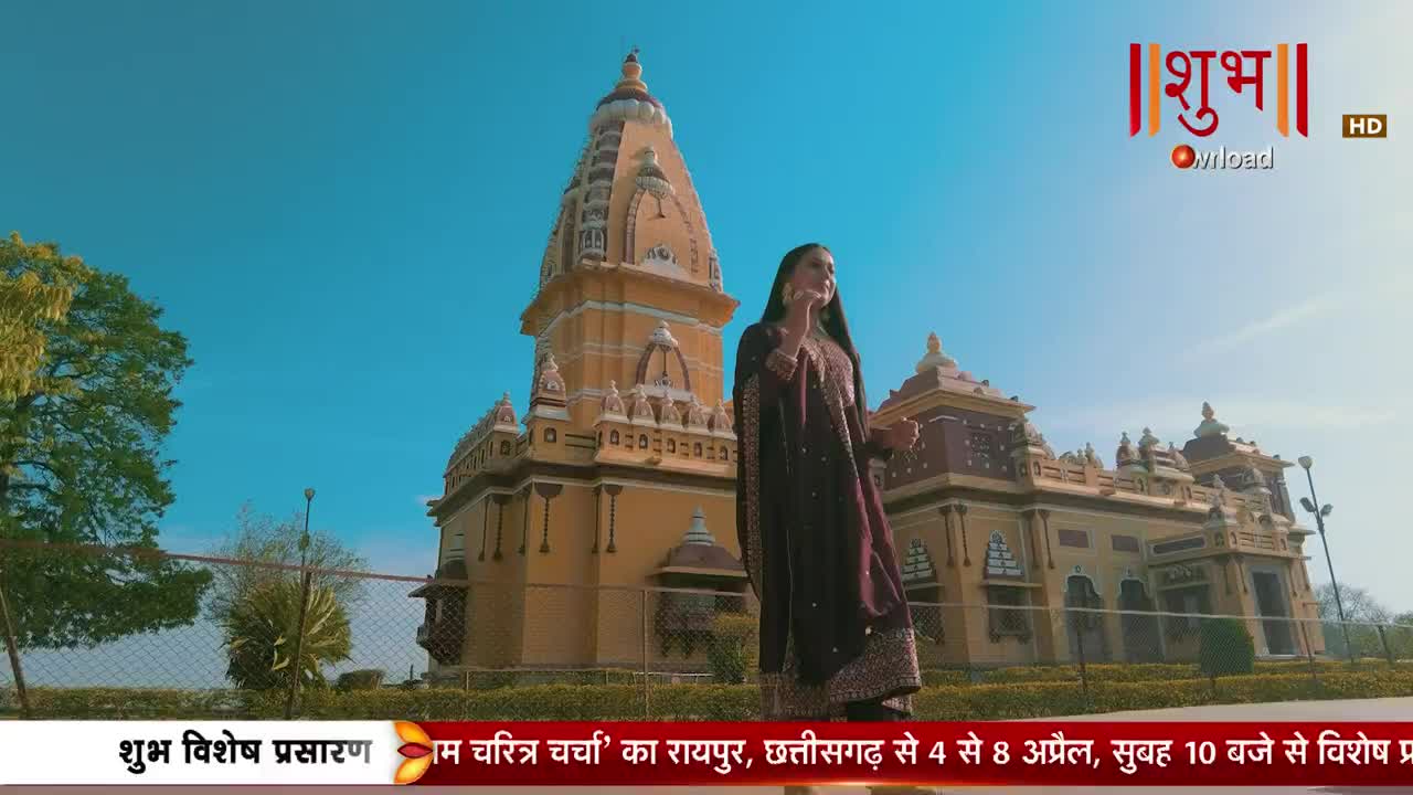 A woman in a deep maroon outfit stands before a grand, ornate temple under a clear blue sky. The Shubh TV logo is visible in the upper right corner.