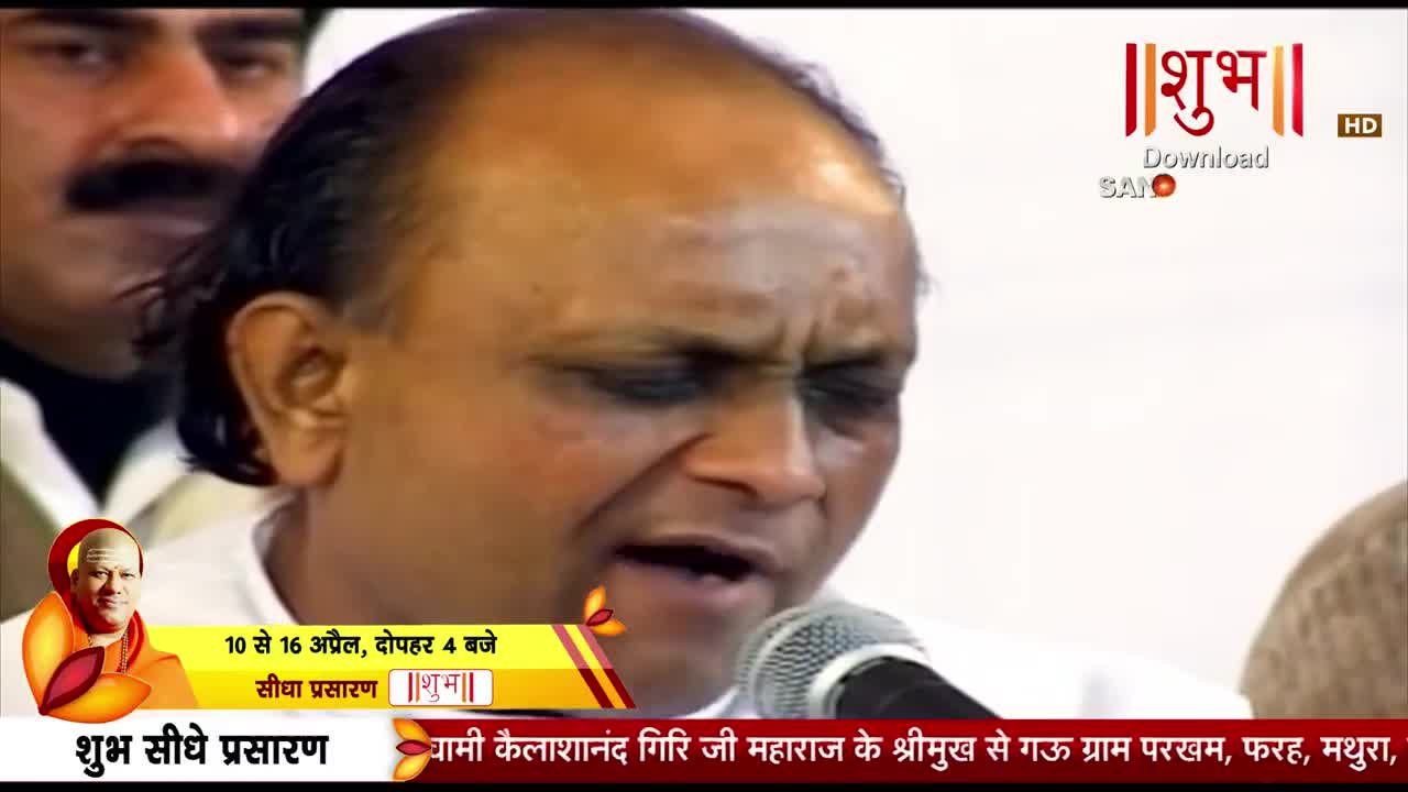 A man with a microphone before him speaks into it, his eyes closed. Behind him, another man with a mustache watches intently.