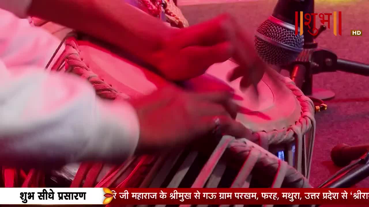 Fingers dance across the tabla, creating a rhythmic pulse. The bright stage lights cast a warm glow on the performance.