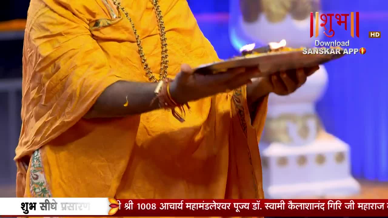 A person in an orange robe holds a brass plate with lit diyas. The Shubh TV logo is visible in the background.