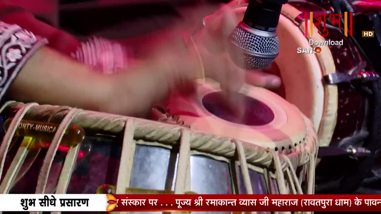 Hands dance across the tabla, a rhythmic beat filling the air. A microphone hangs overhead, capturing the performance for Shubh TV. Hands dance across the tabla, a rhythmic beat filling the air. A microphone hangs overhead, capturing the performance for Shubh TV.