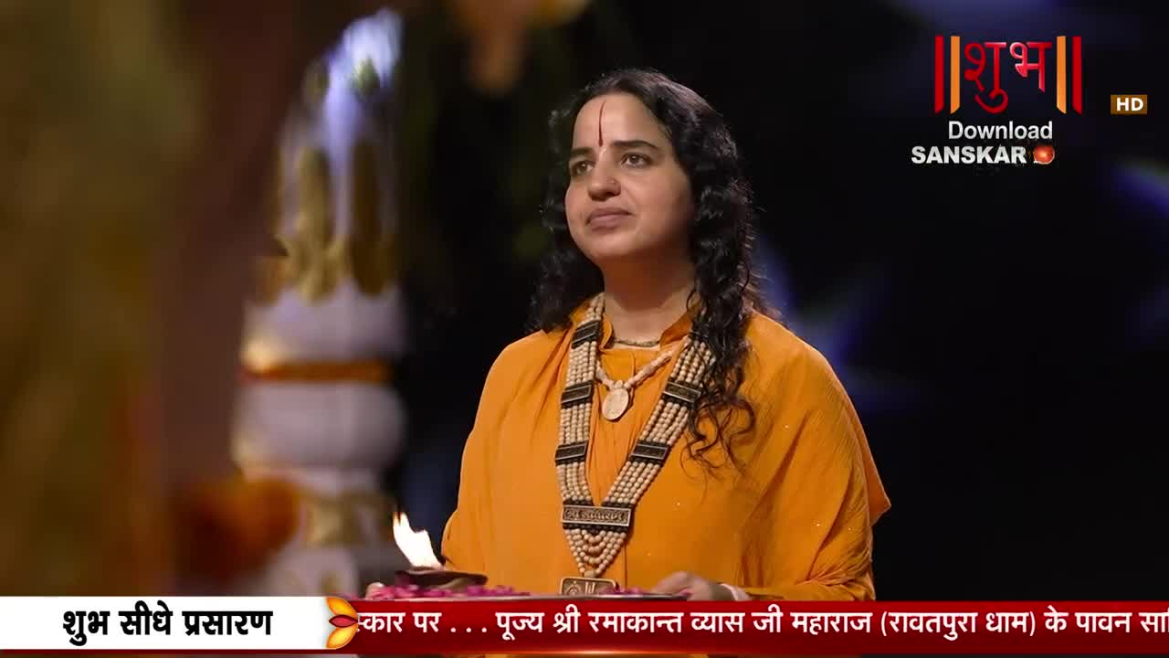 A woman in an orange sari stands before a small oil lamp, her gaze directed upwards. The Shubh Sanskar logo is visible in the background. A woman in an orange sari stands before a small oil lamp, her gaze directed upwards. The Shubh Sanskar logo is visible in the background.