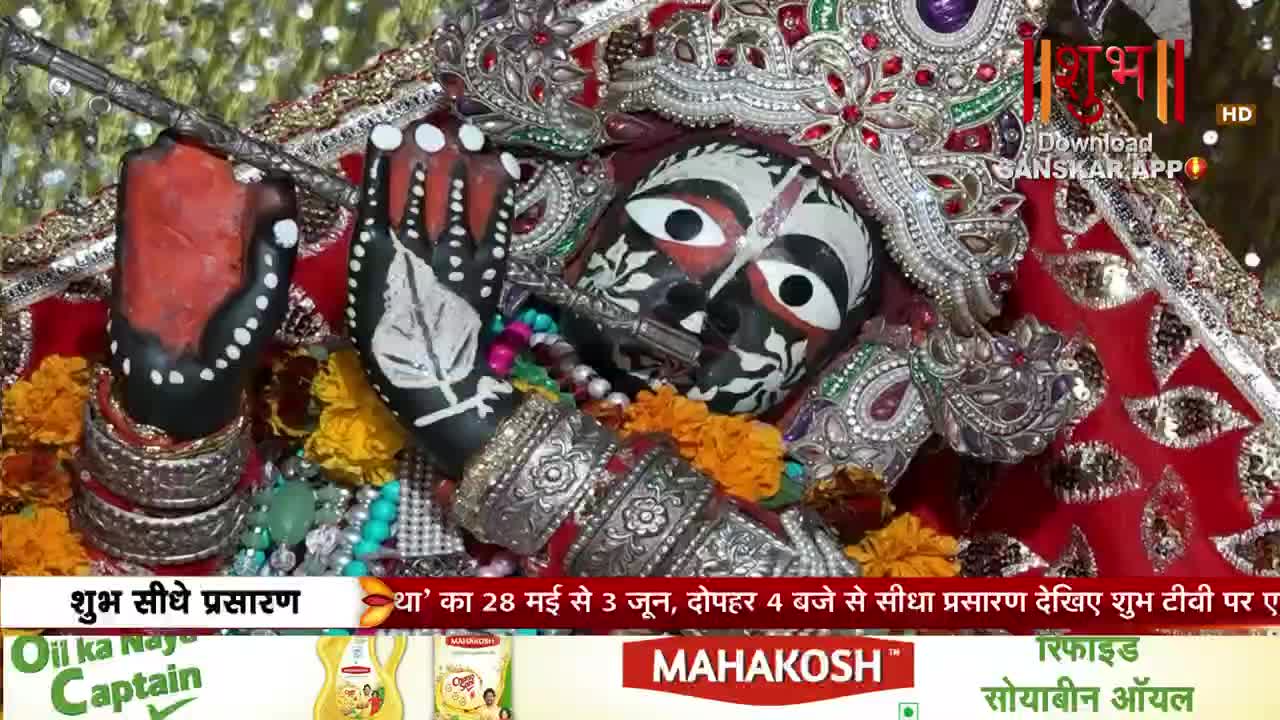 A decorated deity with large, painted eyes and a flute held to its lips rests amidst vibrant garlands and ornate silver bangles. The Shubh TV logo appears in the upper right corner, indicating a live broadcast.