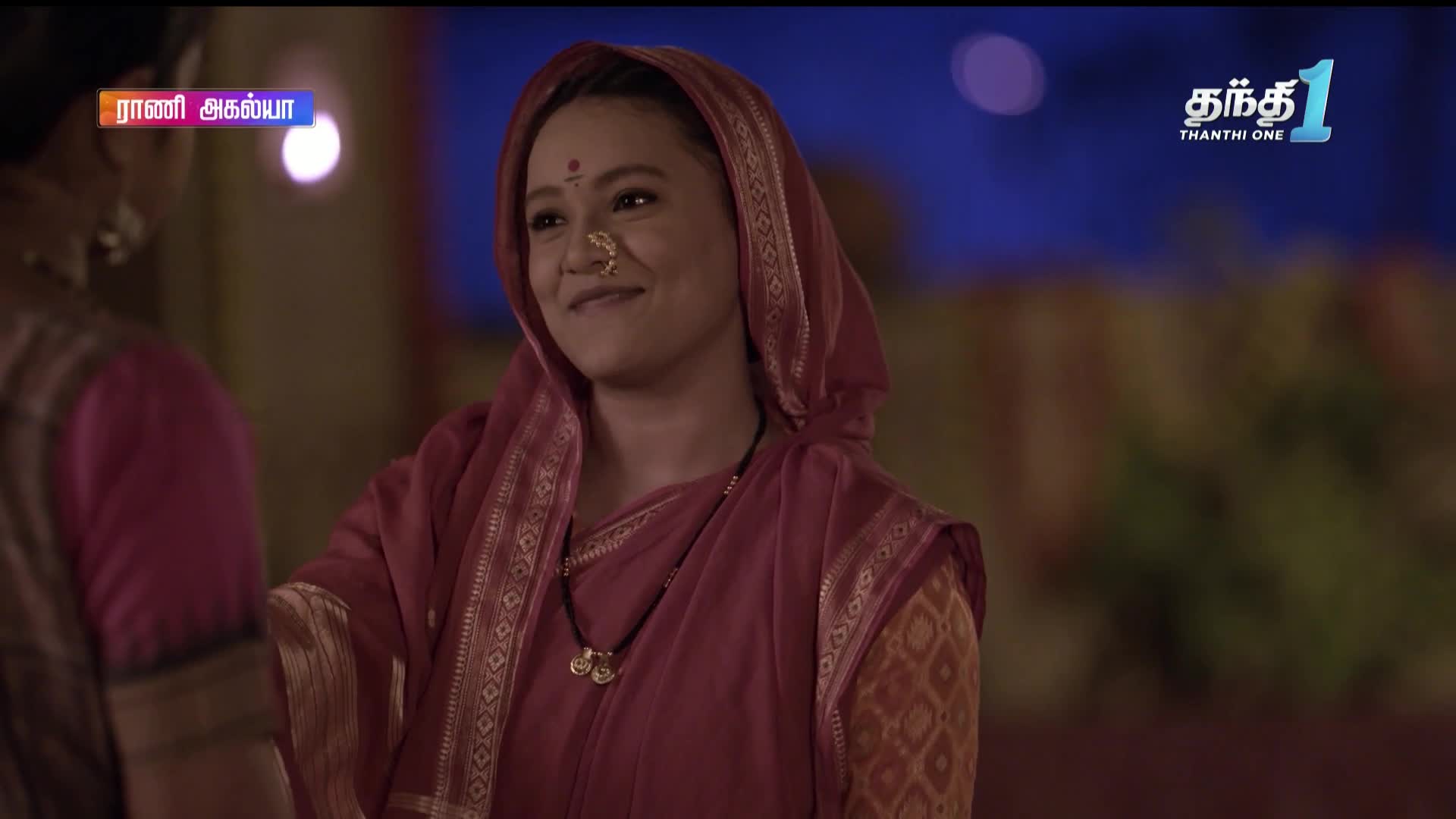 A woman in a red sari smiles, looking towards someone just out of frame. The Thanthi One logo is in the corner, and a show title is displayed above.
