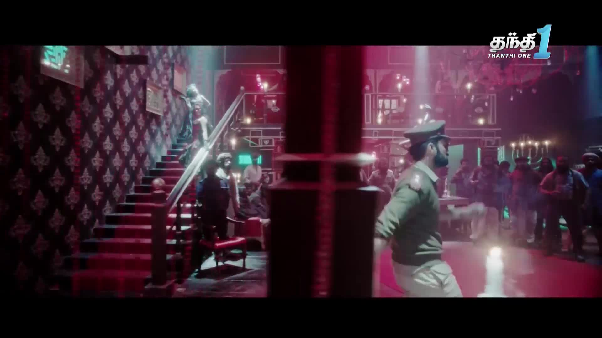 A uniformed officer moves across the dance floor, while figures ascend a staircase. The scene, bathed in red and blue light, unfolds in what looks like a club, as seen on Thanthi One in India.
