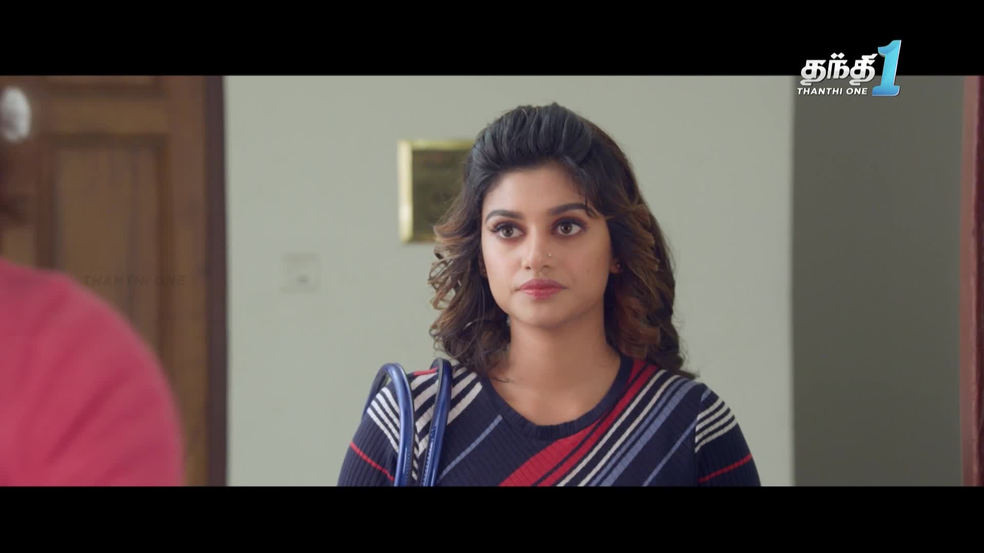 A woman with curly hair and a striped sweater looks directly at someone off-screen. The Thanthi One logo is visible in the top right corner.
