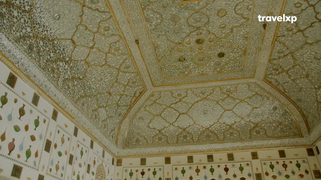 Intricate white patterns cover the ceiling, framed by gold accents. Below, the walls are decorated with colorful, stylized vases and other shapes.
