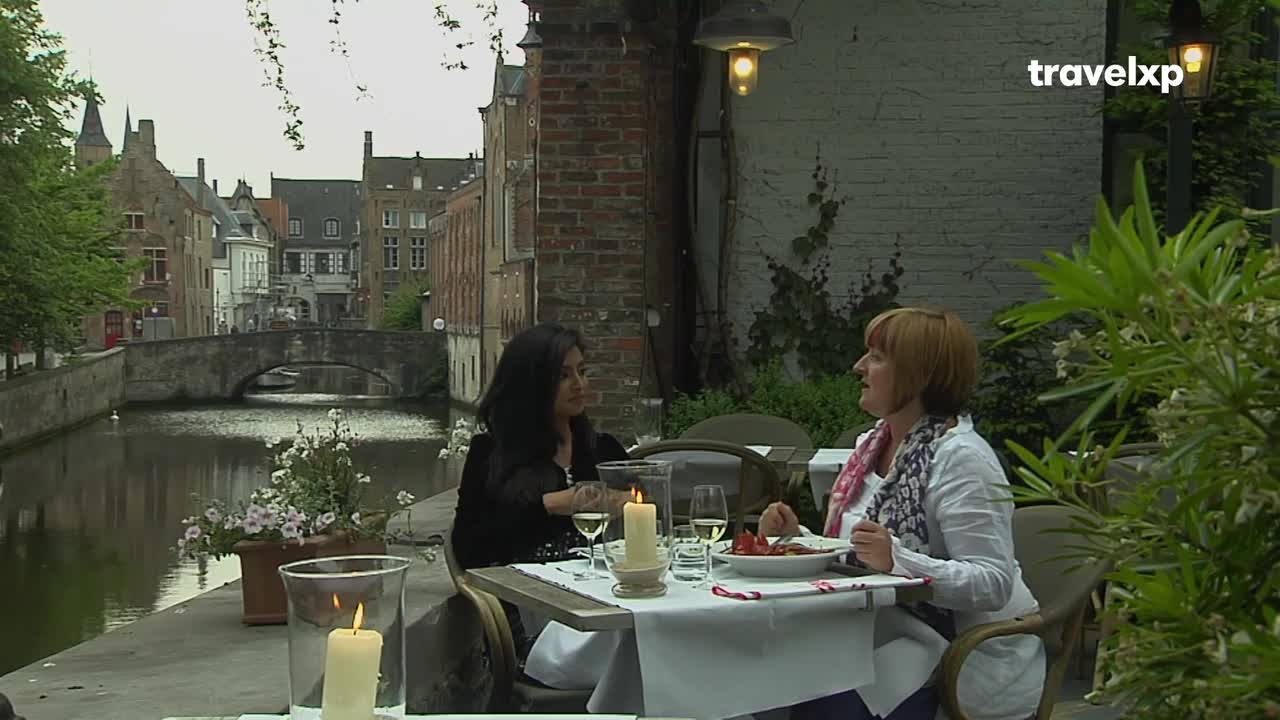 Two women are enjoying a meal at a canalside cafe. The gentle flow of the water reflects the old brick buildings lining the waterway. Two women are enjoying a meal at a canalside cafe. The gentle flow of the water reflects the old brick buildings lining the waterway.
